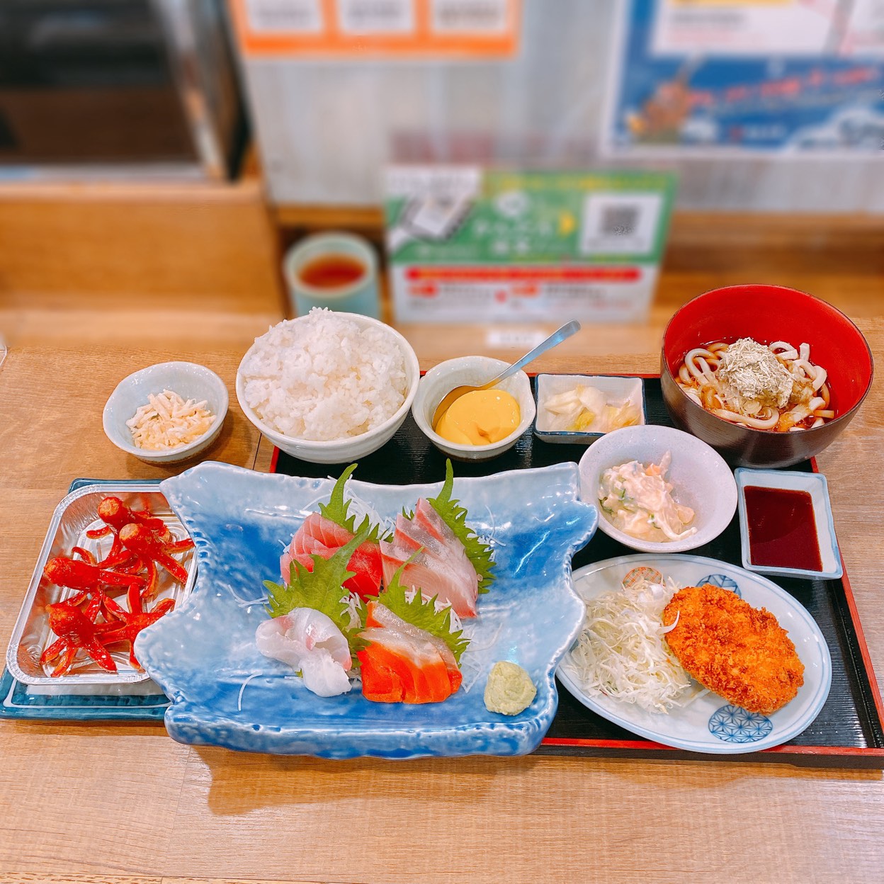 ◆お刺身盛り合わせ定食 1,495円(税込)
◆タコさんウィンナー (アプリ会員入会記念無料サービス)
◆おつまみさきいか (アプリ会員無料サービス)
磯丸水産のアプリがリリースされてすぐに登録し初めて利用しました。
ポイント「磯マイル」が溜まります。
入会プレゼントの無料サービスも嬉しいです。
磯丸はよく利用するので有効利用します。
お刺身盛り合わせ定食は今回もご飯を酢飯に変更してもらい、刺身各種もうどんもコロッケも小鉢も全部美味しかったです。
大根のつまはシソの葉に包んでいただきました。